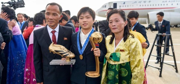 North Korea's Choe Sun (centre) poses for a commemorative photo holding the 2024 FIFA U-20 Women's World Cup trophy at Pyongyang International Airport after returning home on the 28th. Pyongyang/AFP Yonhap News