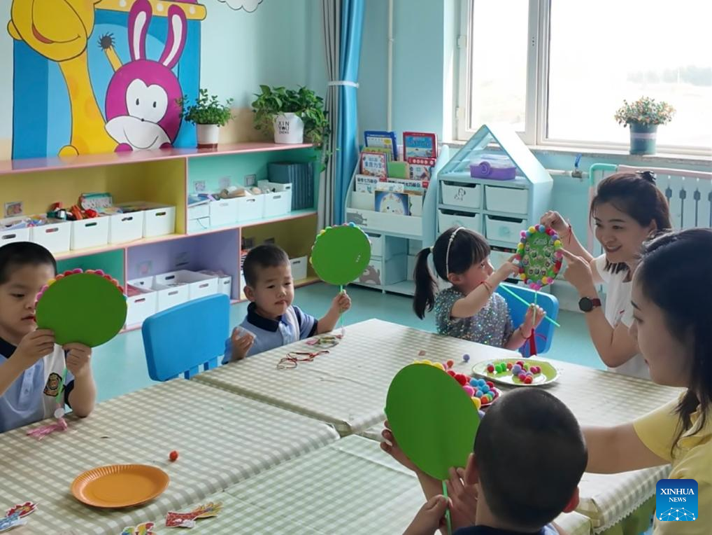 Children make paper ornaments with their teachers at Harbin Children's Home in Harbin, northeast China's Heilongjiang Province, May 30, 2025. (Xinhua/Shen Yijin)