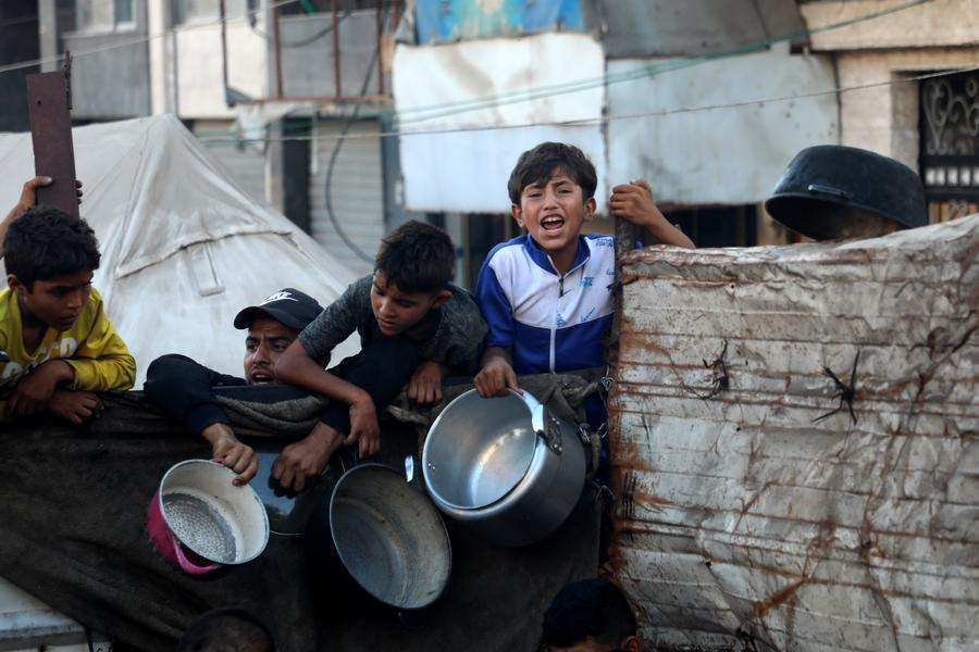 Palestinians wait to receive food in the Al-Rimal neighborhood of central Gaza City, on July 20, 2025. (Photo by Rizek Abdeljawad/Xinhua)