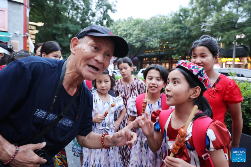 Patimanhan Parihat (R) communicates with a local resident in Beijing, capital of China, July 28, 2025.