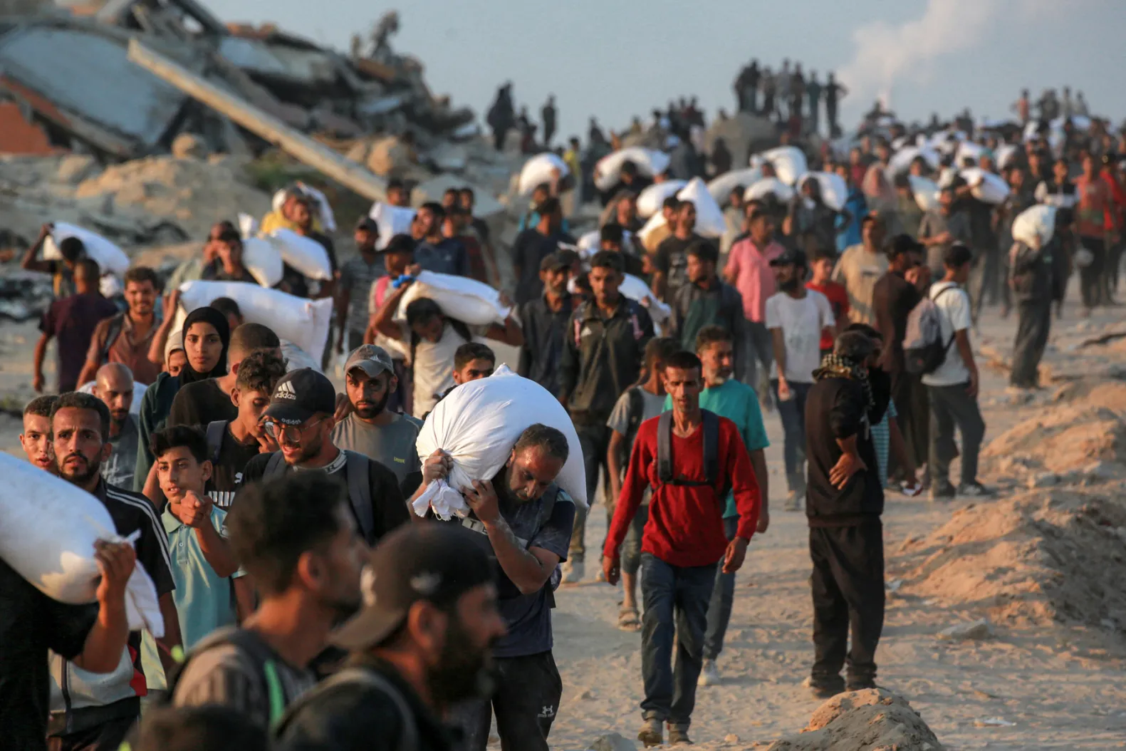People carrying sacks of flour walk along al-Rashid street in western Jabalia on June 17, 2025.