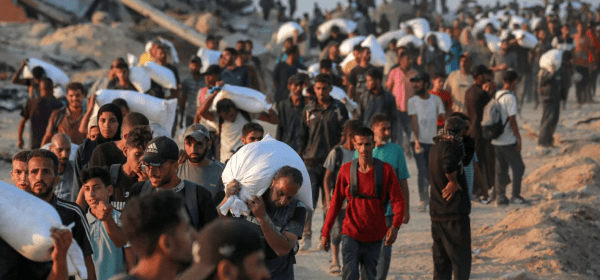 People carrying sacks of flour walk along al-Rashid street in western Jabalia on June 17, 2025.
