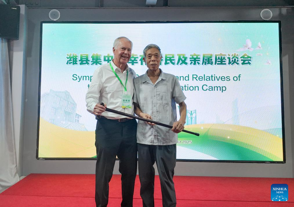 Han Chongbin (R), whose father once aided expatriates at the Weihsien concentration camp, presents a gift cane to Charlie Stanley at a symposium at Weihsien West Civilians Concentration Camp Site Museum in Weifang, east China's Shandong Province, Aug. 17, 2025. (Weihsien West Civilians Concentration Camp Site Museum/Handout via Xinhua)