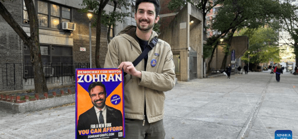 This photo taken with a mobile phone shows a supporter presenting a poster of Democratic candidate Zohran Mamdani during the New York City mayoral election in New York City, the United States, Nov. 4, 2025. Democratic candidate Zohran Mamdani won the New York City mayoral election Tuesday night, becoming the first muslim mayor of the most populous city in the United States. (Photo by Winston Zhou/Xinhua)