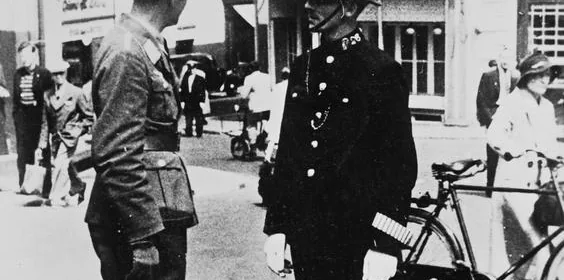 "A German air force officer talking to a British policeman in a Jersey street shortly after the occupation of the island (1940)". Photographs of the iconic British bobby cooperating with Reich authorities had immense propaganda value for the Germans